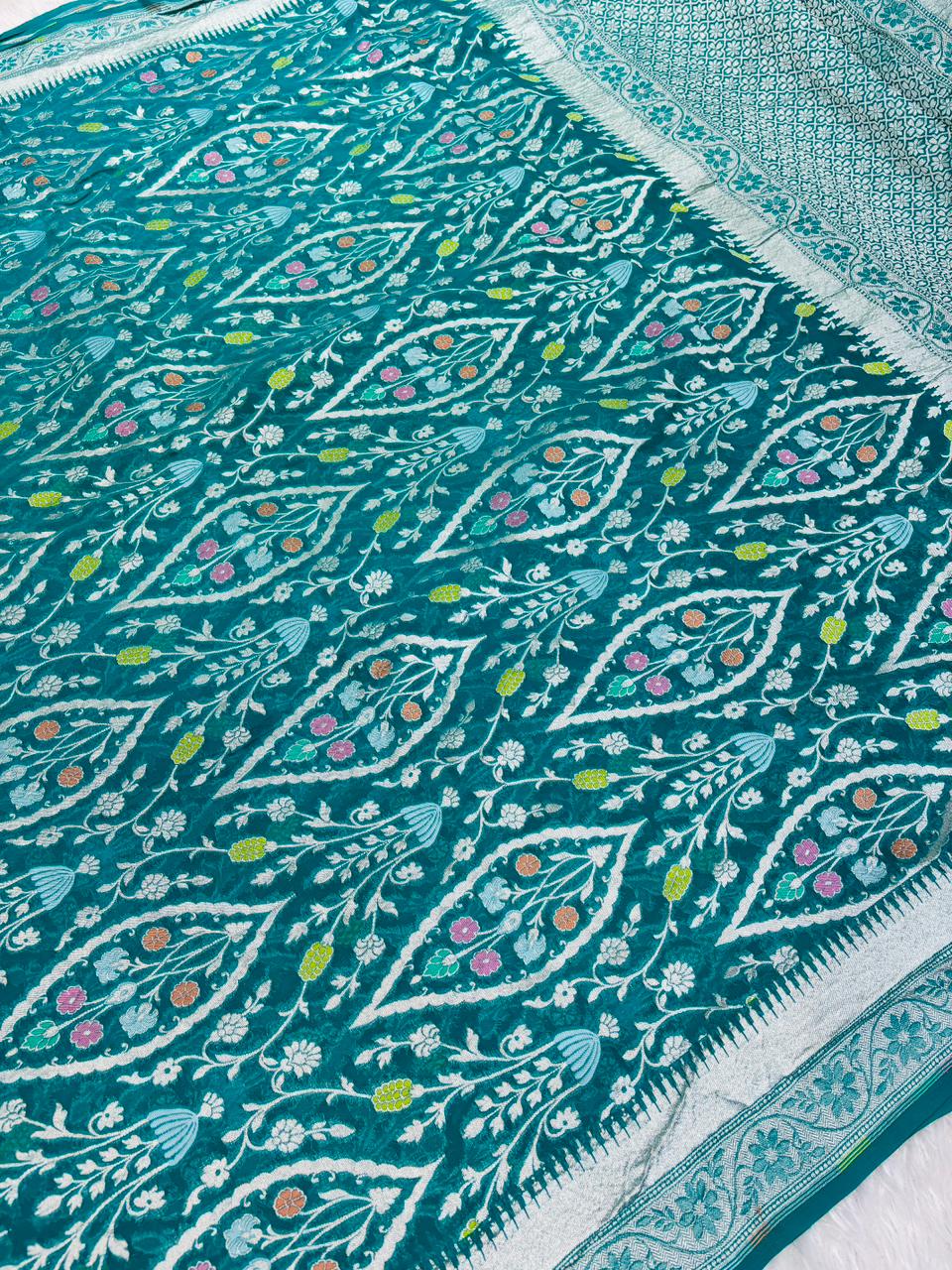 సిల్వర్ జరీ &amp; డైమండ్ మీనాకరి జాల్‌తో కూడిన అద్భుతమైన టీల్ బ్లూ బనారసీ ఖడ్డీ జార్జెట్ చీర